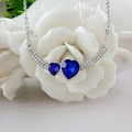 Elegante collana con pendente a doppio cuore blu e cristalli su una base a fiore bianco - Blu Zaffiro