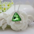 Close-up of a triangle green crystal pendant necklace displayed on a white ceramic flower - Green