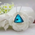 Sky blue triangular crystal pendant necklace with silver chain on decorative background - Aquamarine