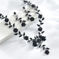 Nahaufnahme von schwarzem Kristallschmuck-Set mit Blumendesign und Tropfensteinen - Schwarz