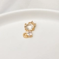 Macro di ciondolo a gatto dorato con zirconi a goccia su un piatto in ceramica bianca - Hello Kitty