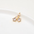 Detailed close-up of a gold-plated cherry pendant with sparkling cubic zirconia on white ceramic - Style 1 / White Cherry