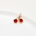 Macro shot of gold-plated cherry pendant with faceted red zircon on white porcelain - Style 1 / Red Cherry