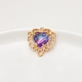 Macro shot of heart-shaped gradient gem pendant with gold hollow lace border - Pink Blue Gradient