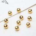 Macro shot of 10 gold-plated round spacer beads on a textured white fabric background - Polished Ball / 6mm (ai-100 Pieces/Pack)