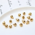 Close-up of small polished gold bell pendants with top rings for DIY jewelry making - 6mm