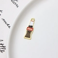 Macro view of a red enamel cola bottle pendant for DIY jewelry on a ceramic plate - Minimum 10 Pcs / Cola