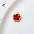 Gros plan du pendentif fleur rouge 12mm avec bordure dorée sur céramique blanche - Rouge