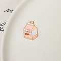Detailed macro view of a pink cherry milk carton enamel charm with gold metal edges - Pink Cherry Milk Carton