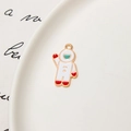 Detailed view of an enamel astronaut charm with gold accents on a white tray - Astronaut 05
