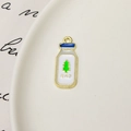 Vue détaillée d'un pendentif émaillé en forme de bouteille de lait avec bordure dorée - Bouteille de Lait Texte Japonais