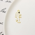 Macro detail of enamel astronaut charm in gold alloy on a white ceramic plate - Astronaut 08