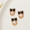 Detail view of black enamel bow pearl pendants for DIY necklaces and earrings in a white tray - Black