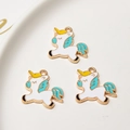 Detailed macro view of three white enamel unicorn charms with gold plating for DIY jewelry - Light Blue