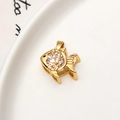 Detailed macro view of a gold fish pendant with zircon inlay on a ceramic background - White Zirconia Fish Style