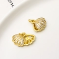Detailed close-up of shell shaped gold plated jewelry charm with micro-pave white zircons - Shell