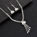 Detailopname van zilveren bruidsketting en oorbellen met kwastjes op zwarte textuur - Stijl 698 Glas Oorknopjes (Ketting Oorbellen)