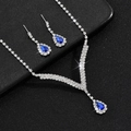 Macro-opname van V-vormige zilveren ketting en oorbellen set met blauwe kristallen - Zilver Koningsblauw Tweedelige Set