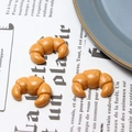 Set of three golden-brown resin croissant miniatures with white sugar powder detail - Croissant