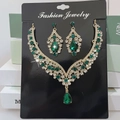 Detail of vintage gold alloy jewelry set featuring teardrop green gemstones and rhinestones - Gold White Green