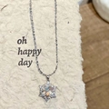Macro shot of silver snowflake necklace with refractive crystal pendant on display card - White