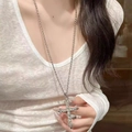 Gothic punk lange kruis ketting met witte zirkonia gedragen door een model - Enkellaagse zirkonia kruisketting (Schakelketting)