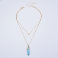 Detail of layered gold necklace featuring a heart pendant and blue hexagonal crystal - Turquoise