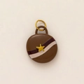 Detailed view of a round chocolate brown pendant featuring a golden star and striped design - Oval River Style