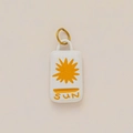Detailed macro view of white ceramic sun pendant with golden metal loop and engraving - Square Bee Style
