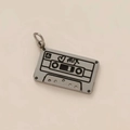 Macro detail of a vintage cassette tape pendant in antique silver with engraved heart patterns - Cassette Tape