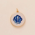Gold plated circular charm with dark blue seashell illustration and white matte background - Blue Shell Pendant