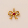 Gros plan d'un pendentif nœud doré orné d'une pierre précieuse rouge en forme de cœur - Pendentif Noeud Papillon Doré