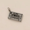 Gros plan détaillé d'un pendentif cassette rétro en métal avec gravure cœur et MIX - Cassette Audio