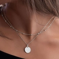 Double-layered silver necklace with small metal beads and a polished flat round pendant - Silver (White K)