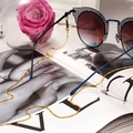 Chaîne de lunettes dorée tendance avec lunettes de soleil dégradées sur un magazine - Doré