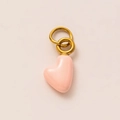 Detailed view of a pink heart-shaped pendant with polished gold vacuum-plated metal rings - October Heart Pendant / Pink