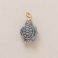 Detail macro view of a grey ceramic turtle charm with a metallic gold loop connector - Tortoise Pendant