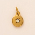 Detailed view of a gold starburst pendant with a rainbow rhinestone and engraving - June Birthstone Pendant