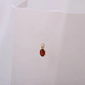 Detailed view of an oval red zircon pendant with a golden four-claw setting for jewelry - January Birthstone Pendant