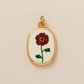 Détail macro du pendentif ovale doré avec illustration de fleur rouge rétro sur blanc - Pendentif Fleur d'Août