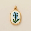 Vue détaillée d'un pendentif ovale doré avec fleurs bleues sur base en céramique - Pendentif Fleur de Juillet