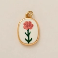 Detail van vintage ovale gouden hanger met roze bloemen op een beige achtergrond - Januari Bloemenhanger