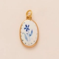 Detail van ovale titaanstalen hanger met blauwe bloemmotieven en gouden frame - Ronde Blauwe Bloem