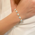 Macro shot of gold-plated evil eye bracelet with white enamel charms on a wrist - White