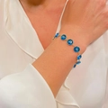 Evil Eye charm bracelet in gold finish with blue enamel pendants worn on wrist - Dark Blue