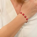 Close-up of red Evil Eye enamel bracelet on model with golden chain and charms - Red