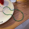 Groene kralenketting met zilveren karabijnsluiting op een rustieke houten tafel - Groen
