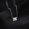 Silver four-leaf clover pendant necklace with sparkling pavé crystals on a black fabric background - Silver