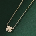 Elegant gold clover pendant necklace with sparkling white zircons on dark green texture - Gold