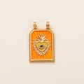Detail of a tarot-style gold pendant with orange enamel heart and evil eye motif - Yellow Sacred Heart